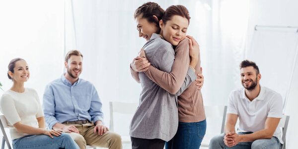 panoramic shot of women hugging during group therapy session