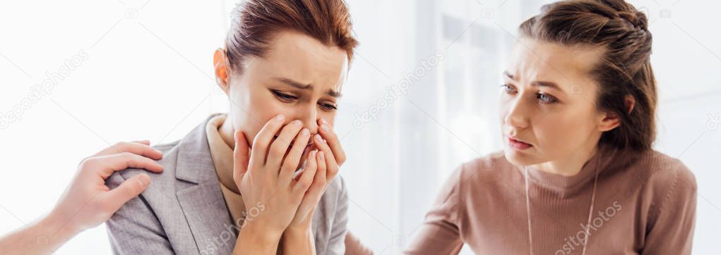 panoramic shot of woman consoling another crying woman during therapy meeting