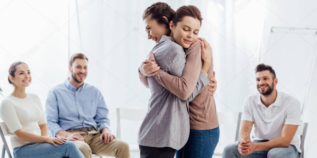 panoramic shot of women hugging during group therapy session