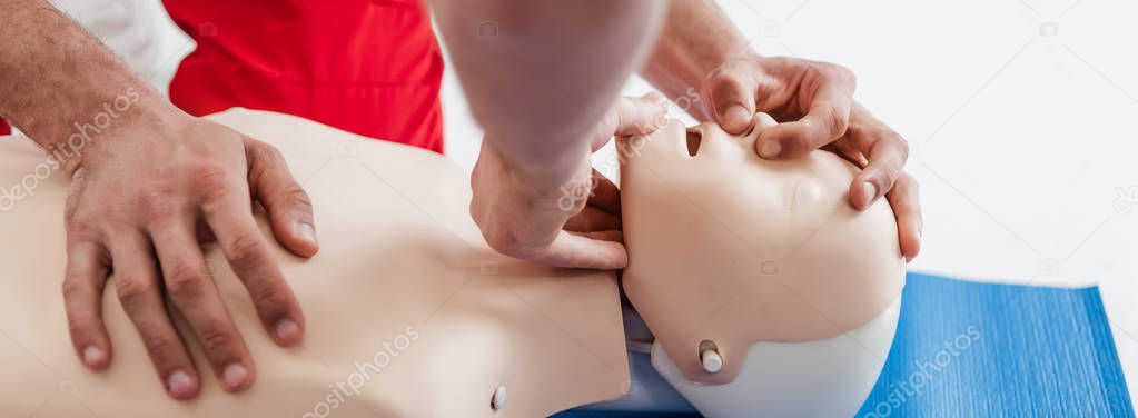 panoramic shot of men practicing cpr technique on dummy during first aid training