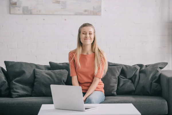 Veselă Blondă Freelancer Stând Canapea Lângă Laptop Acasă — Fotografie, imagine de stoc