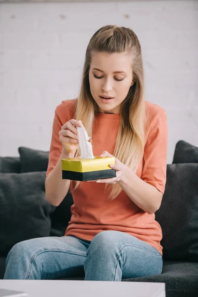 Blonde Woman Holding Tissue Box While Sitting Sofa Home — Stock Photo, Image