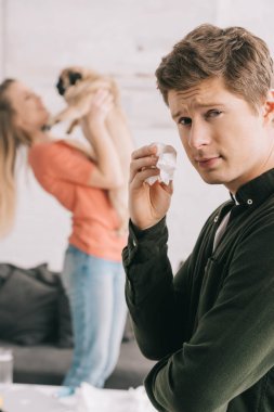 seçici odak yakışıklı adamın doku tutarak ve kamera kız ve evde beslenen hayvan yakın bakarak köpek alerjisi