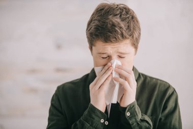 man having allergy and sneezing in tissue at home  clipart