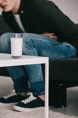 mide tutarak ve kahve masanın bir bardak süt ile adam görünümünü kırpılmış 