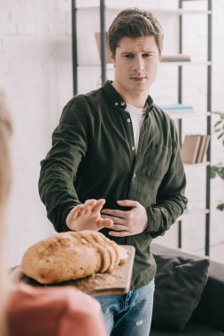 kırpılan görünümünü kesme tahtası ile yakışıklı adam yakınındaki dilimlenmiş ekmek gluten intoleransı ile tutan kadın 