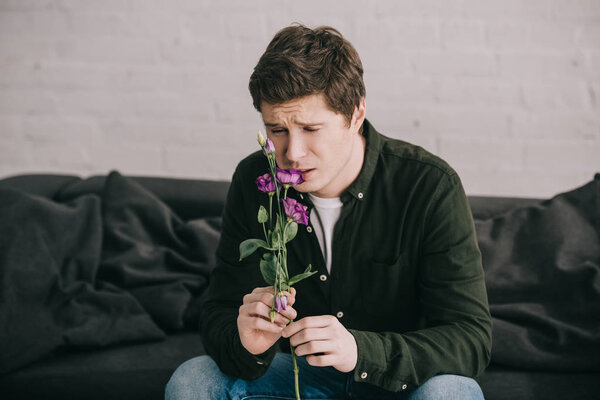 handsome man smelling flower while sitting at home