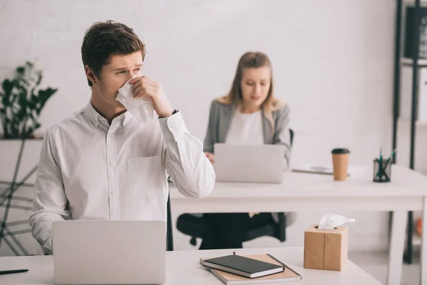 Selective Focus Businessman Sneezing Tissue While Using Laptop Businesswoman Office — Stock Photo, Image