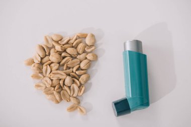 top view of tasty nutritious peanuts near blue inhaler on grey  clipart