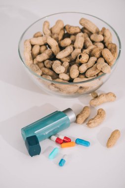 Mavi inhaler ve gri haplarla besleyici fıstık ile cam kase 
