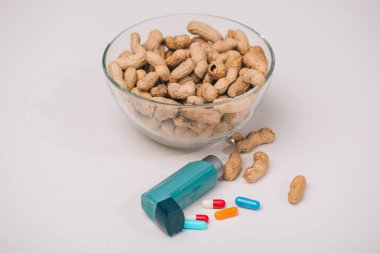 Mavi inhaler ve gri haplarla lezzetli fıstık ile cam kase 