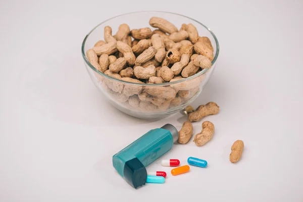 青い吸入器と灰色の錠剤の近くおいしいピーナッツとガラスのボウル — ストック写真