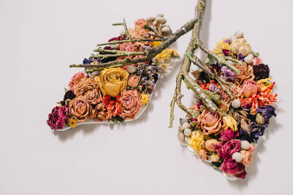 floral composition with dried flowers and twigs in shape of lungs on grey 