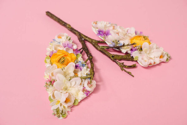 floral composition with blooming flowers and twigs in shape of lungs on pink 
