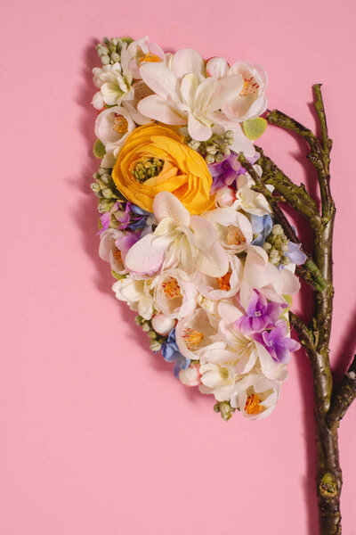 close up of floral composition with blooming flowers and twigs in shape of lungs on pink 