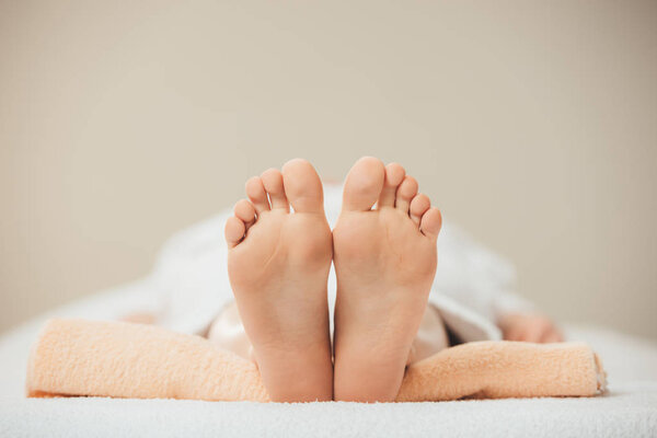 selective focus of adult woman lying on beige towel in spa 