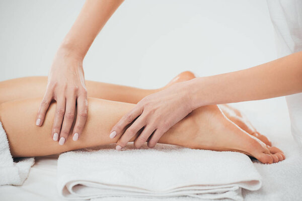 partial view of masseur doing foot massage to adult woman in spa