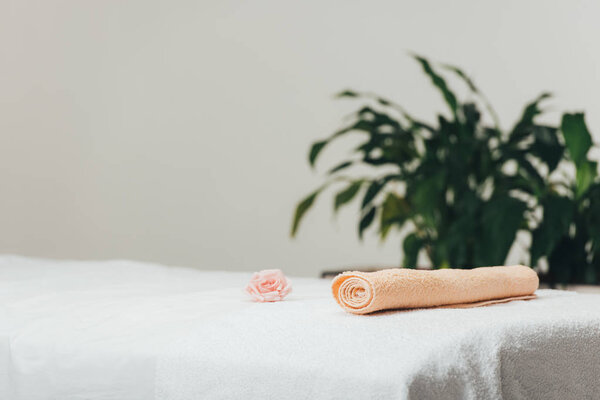 selective focus of massage table with rose and beige towel in spa 