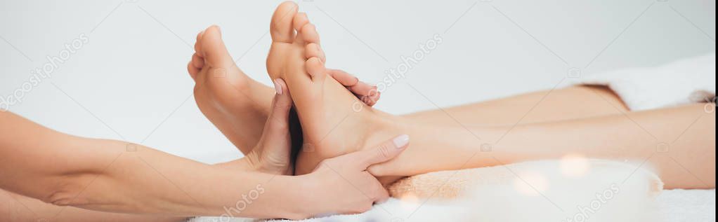 panoramic shot of masseur doing foot massage to adult woman in spa