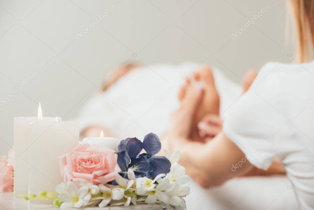 cropped view of masseur doing foot massage to adult woman in spa
