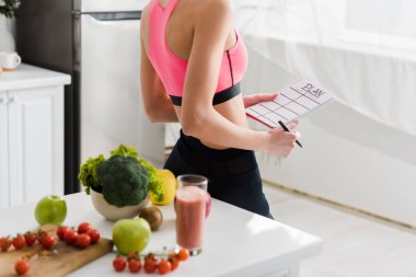 Mutfakta plan yazı ile spor giyim tutan kadın kırpılmış görünümü 