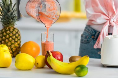 Cam lezzetli Smoothie dökme genç kadının kırpılmış görünümü  