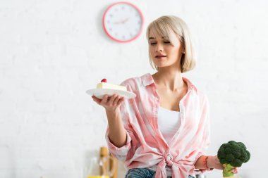 organik brokoli tutarken tatlı kek ile uçan bakıyor sarışın kız