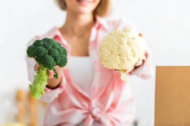 cropped view of girl holding cauliflower and broccoli  clipart