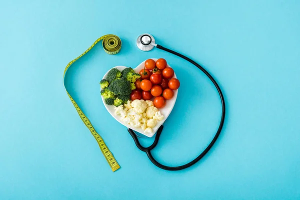 Organiczne Warzywa Płytce Kształcie Serca Pobliżu Taśmy Pomiarowej Stetoskop Niebiesko — Zdjęcie stockowe