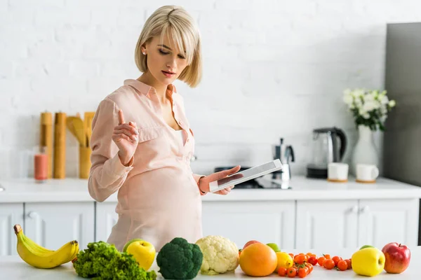 Aantrekkelijke Zwangere Vrouw Bedrijf Digitale Tablet Kijken Naar Groenten Fruit — Stockfoto