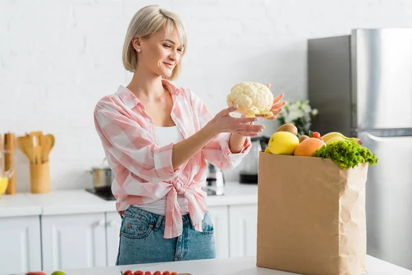 Chica Rubia Feliz Sosteniendo Coliflor Cerca Bolsa Papel Con Comestibles — Foto de Stock