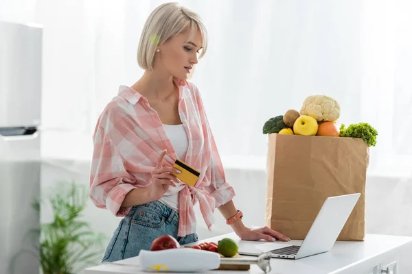 Mujer Joven Rubia Sosteniendo Tarjeta Crédito Mientras Usa Ordenador Portátil — Foto de Stock