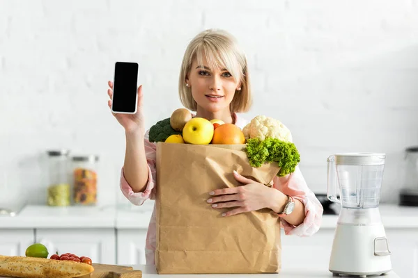 Blonde Girl Holding Smartphone Blank Screen Paper Bag Groceries — Stock Photo, Image