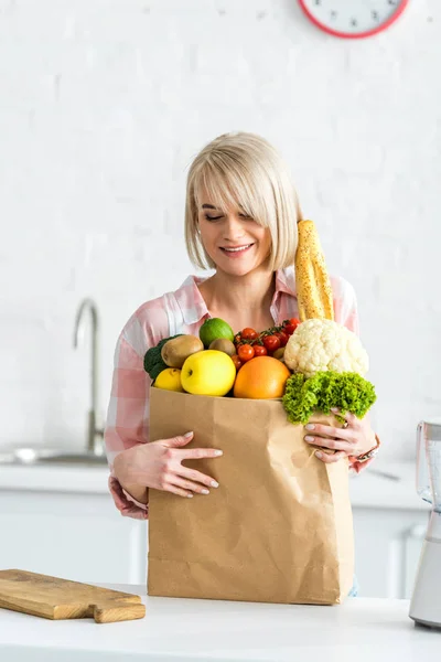 Приваблива Весела Блондинка Молода Жінка Дивиться Паперовий Мішок Продуктами — стокове фото