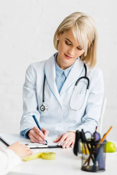 Attractive Blonde Nutritionist Writing Diagnosis Patient — Stock Photo, Image