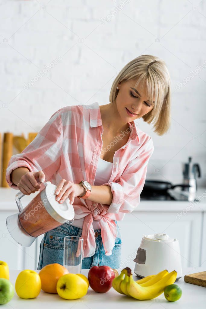 happy young woman holding blender with delicious smoothie near glass  