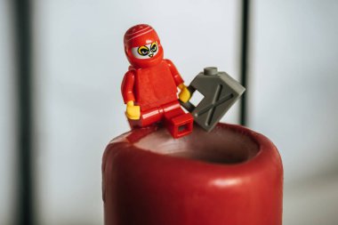 KYIV, UKRAINE - MARCH 15, 2019: close up view of plastic lego figurine with can of gasoline on candle clipart