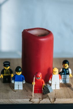 KYIV, UKRAINE - MARCH 15, 2019: red figurine with can of gasoline and match standing with lego characters near candle clipart