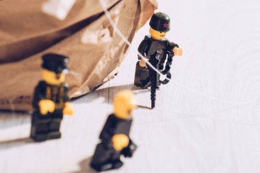KYIV, UKRAINE - MARCH 15, 2019: lego policemen minifigures with gun and handcuffs on white table clipart