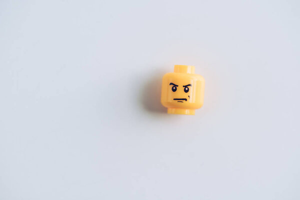 KYIV, UKRAINE - MARCH 15, 2019: top view of lego figurine head with angry face on white with copy space