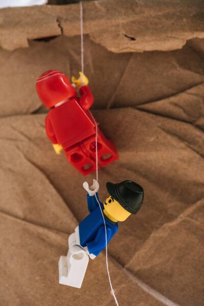 KYIV, UKRAINE - MARCH 15, 2019: close up view of red and blue plastic lego figurines climbing rope 