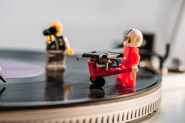 KYIV, UKRAINE - MARCH 15, 2019: selective focus of plastic lego figurine with toy trolley on vinyl record player