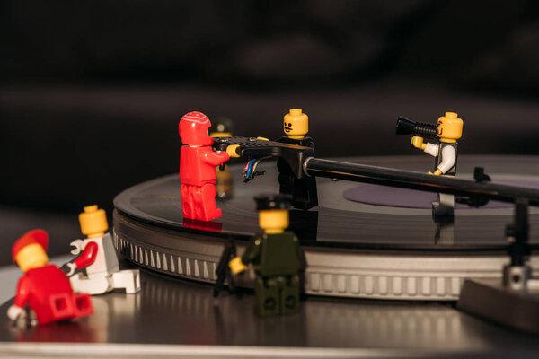 KYIV, UKRAINE - MARCH 15, 2019: close up view of plastic lego figurines fixing vinyl record player