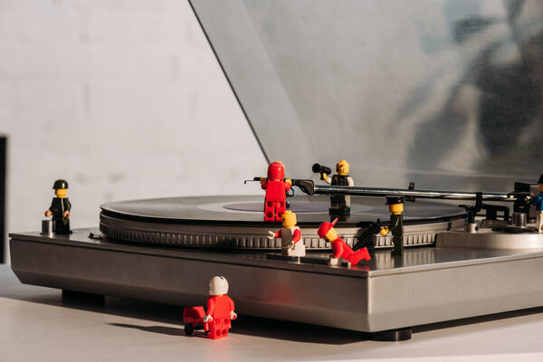 KYIV, UKRAINE - MARCH 15, 2019: colorful plastic lego figurines fixing vinyl record player