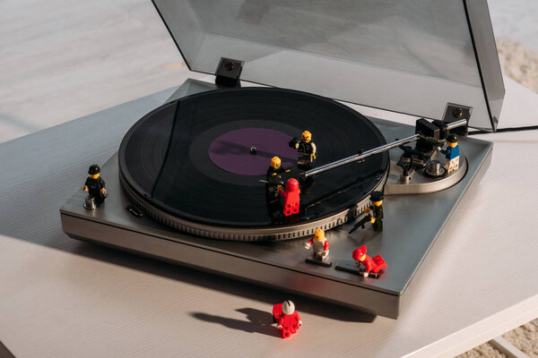 KYIV, UKRAINE - MARCH 15, 2019: plastic lego figurines on vinyl record player on white table