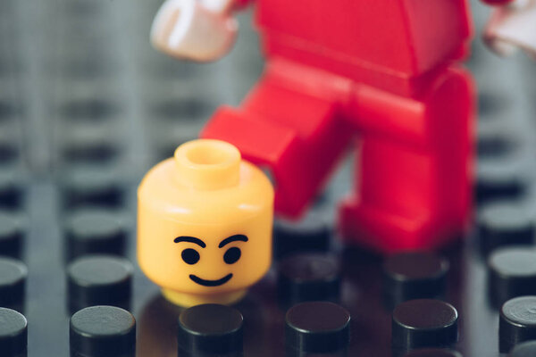 КИЕВ, УКРАИНА - 15 марта 2019 года: Выборочный фокус головы с смайликом рядом с красной фигуркой лего на черных блоках лего
