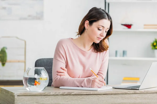 Atractiva Mujer Concentrada Escribiendo Cuaderno Mientras Está Sentada Mesa Casa — Foto de Stock