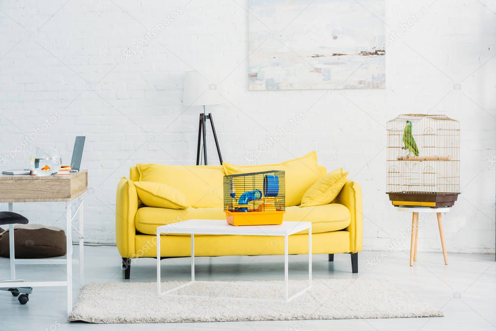 spacious, light living room with yellow sofa near white brick wall