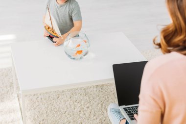 kadın dizüstü bilgisayar kullanarak kısmi görünümü ve çocuk balık kase ile tablo yakın ahşap gemi modeli tutarak