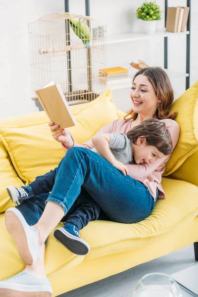 Sonriente Madre Con Libro Divirtiéndose Con Adorable Hijo Sofá Casa —  Fotos de Stock